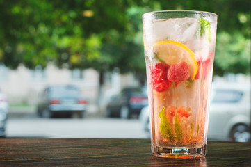 glass of water with ice and lemon on wooden table