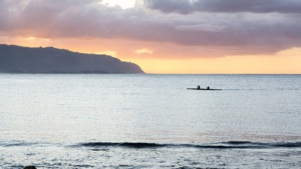 Obraz premium Outrigger canoes at sunset at Haleiwa Hawaii Oahu orange clouds with blank space for copy