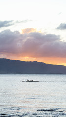 Fototapeta na wymiar Outrigger canoes at sunset at Haleiwa Hawaii Oahu orange clouds with blank space for copy