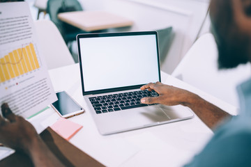 Man surfing on laptop and analyzing paper chart