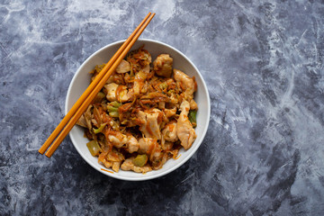 chicken with vegetables in white bowl on ceramic background