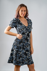Fototapeta premium A girl in a gray dress with drawings of flowers, isolated on a white background.