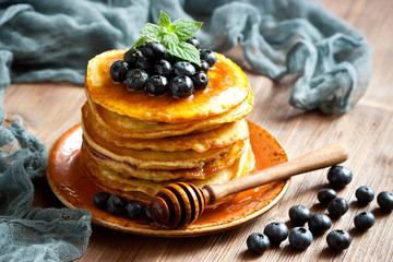 Pancakes with honey   and blueberries on wooden  board