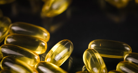 Fish Oil Omega 3 golden capsules on black blackground