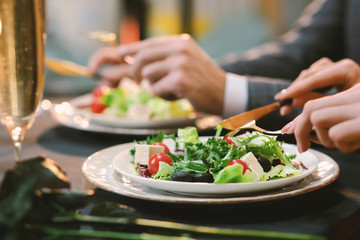 Obraz na płótnie Canvas Closeup Of Unrecognizable Couple Eating Greek Salad At Dinner In Restaurant