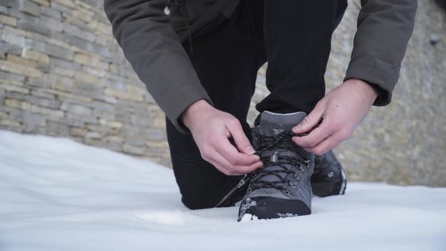 Close up of a hiker tying his boots in snow and walking away