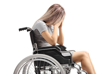 Fototapeta na wymiar Sad female in a wheelchair holding her head