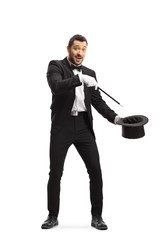 Magician making a magic trick with a wand and a tophat and looking at the camera