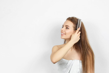 Fototapeta premium Beautiful woman in a towel combing hair.