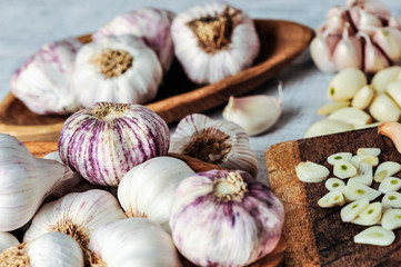 Garlic Cloves and Bulb in wooden bowl on white table.