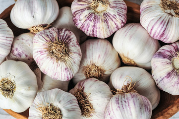 Garlic Cloves and Bulb in wooden bowl on white table.