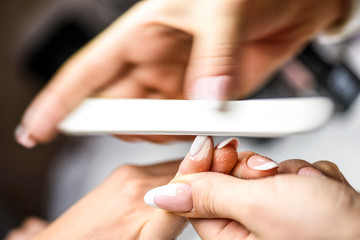 Nails manicure detail in luxury cosmetic salon. Nail art gel modelation. Woman is receiving a manicure by a beautician with nail file close up.