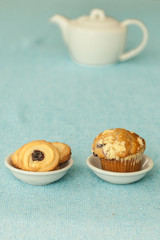 white teapot whit cookies and blueberry muffin