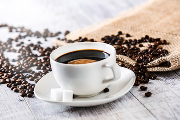 Coffee cup and beans on old white table. Roasted coffee beans top view.
