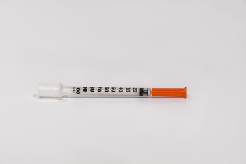 Disposable ejecting liquid plastic insulin syringe tube with a metallic nozzle. Reciprocating pump medical injection with orange cup, stainless steel needle & ml insulin units measurement.