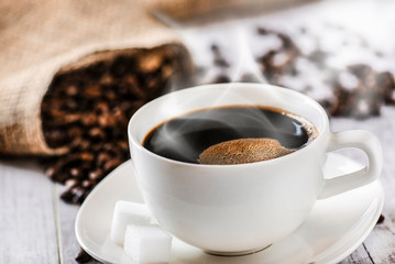 Coffee cup and beans on old white table. Roasted coffee beans top view.