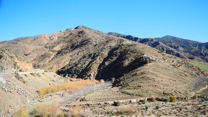Fototapeta premium Bright landscape of Morocco, breathtaking curves of mountains, stunning combination of hills & farm land,inadvertent distribution of houses & huts, raw impression of pure nature.
