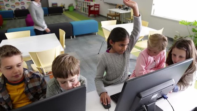 Teacher helping elementary students at computer