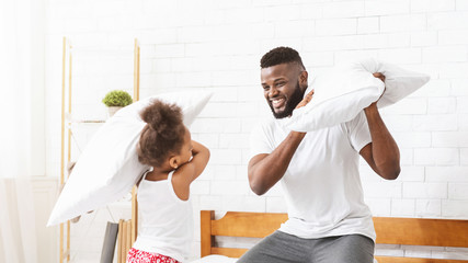 Loving black dad having pillow fight with little playful daughter