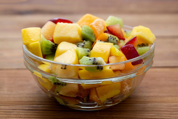 Fresh fruits salad glass bowl - mango, citrus, kiwi fruit, plum and persimmon. Healthy food. Smoothie mix.