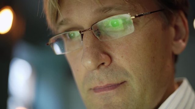 Zoom in closeup face of middle aged man in eyeglasses working on laptop computer and smiling