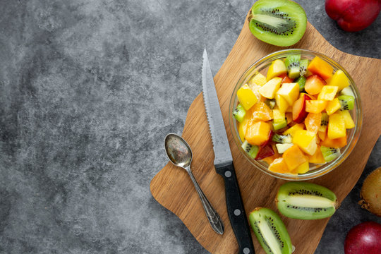 Top view of healthy fruits salad - mango, citrus, kiwi fruit, plum and persimmon. clean eating. Copy space.