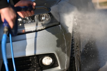 Fototapeta na wymiar Manual car wash with pressurized water jet. Cars cleaning concept.