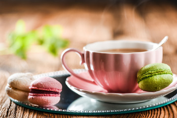 Sweet cake macarons and green tea. Colorful macarons with tea and mint on wooden table.