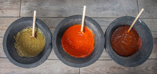 Fototapeta na wymiar Mexican sauces in molcajete of mud, in green colors, pico de gallo, with tomato onion and green chili, circular stone bowl