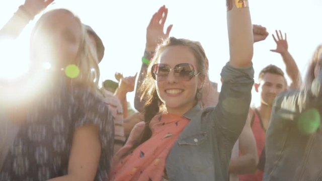Crowd of young energetic friends dancing and cheering at summer music festival