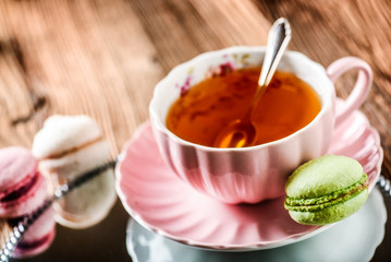 Sweet cake macarons and green tea. Colorful macarons with tea and mint on wooden table.