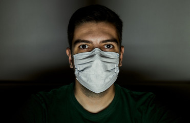 Portrait of a man in a surgical mask to protect against infections. Dark background
