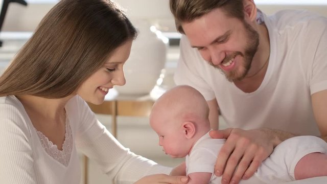 Happy family. Portrait of caucasian smiling mother father and newborn baby hugging at home. Parenthood Motherhood. Loving parents mom dad enjoying caring little child. healthy childcare, 4 K Slow-mo