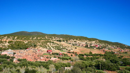 Fototapeta premium Bright landscape of Morocco, breathtaking curves of mountains, stunning combination of hills & farm land,inadvertent distribution of houses & huts, raw impression of pure nature.