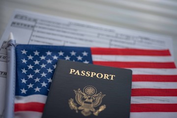 Blurred U.S. standard application certificate of live birth application form next to American flag and Passport of USA. Close up view. © Evgenia Parajanian