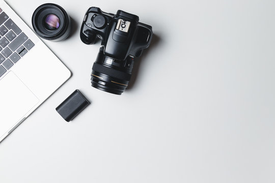 Photographer's workplace on a white background. Modern laptop, digital camera, lens, battery, smartphone. Minimalism. Top view. Copy space. Equipment for the photographer. The concept of freelancing
