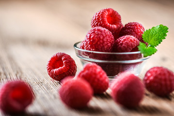 Fresh raspberry in glass bowl, on wooden board. Ripe raspberries freshly collected.
