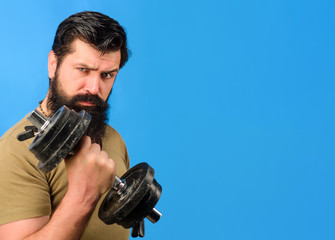 Strong man with dumbbells during an exercise. Bearded man raising dumbbells. Muscular fitness man working out with dumbbells. Sportsman making weightlifting. Handsome sportsman making weightlifting.