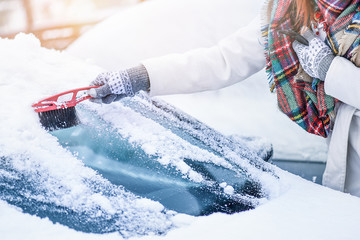 Woman cleaning snow from windshield, Scraping frozen ice glass. Winter car clean front windows.