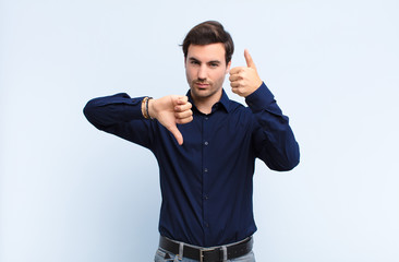 young handsome man feeling confused, clueless and unsure, weighting the good and bad in different...