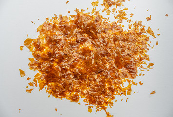 Shellac flakes, shellac is a  resin secreted by the female lac bug. It is dissolved in alcohol to make liquid shellac, which is used as a brush-on colorant, food glaze and wood finish.