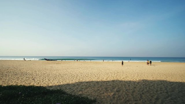 Wide angle reveal shot of Varakala beach in Kerala, India on a bright and sunny morning with waves hitting the shore