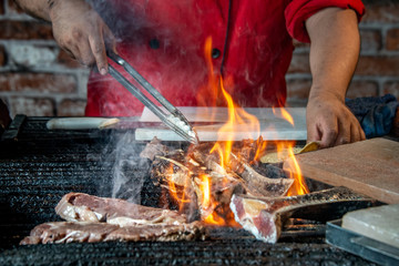 gril grill with roast beef and fire flames, chef cook food on the fathoms, charcoal-roasted food on hot fathoms in restaurant