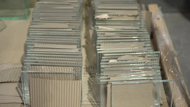 Multiple glass panels stacked in a row with a spacer made by cardboard in between. Stack of glass sheets cut to size in glass factory. 