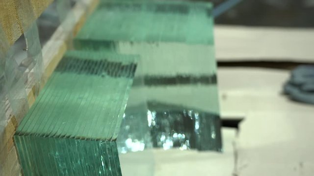 Sheets of factory manufactured tempered clear glass. Stack of glass sheets cut to exact same size stacked in a row in glass factory. Glass cutting industry. 