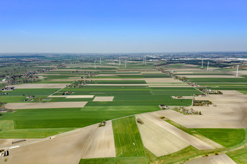 Fototapeta premium Beautiful top view of plowed and sown fields.You can see windmills on the horizon, villages and arable land that create a bizarre pattern on the ground. Shot on drone. 