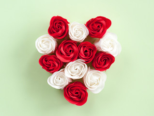 Red and white roses heart-shaped on a green background. Festive background for Valentine's day