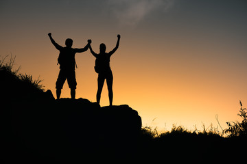 Man and woman celebrating climb to the top of mountain. 