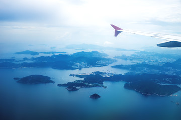 Aerial view of Hong Kong islands in blue morning mood from a flying airplane with wing