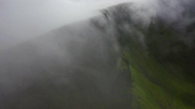 Clouds rolling over clifftops on remote Faroe Islands coastline, aerial time lapse
